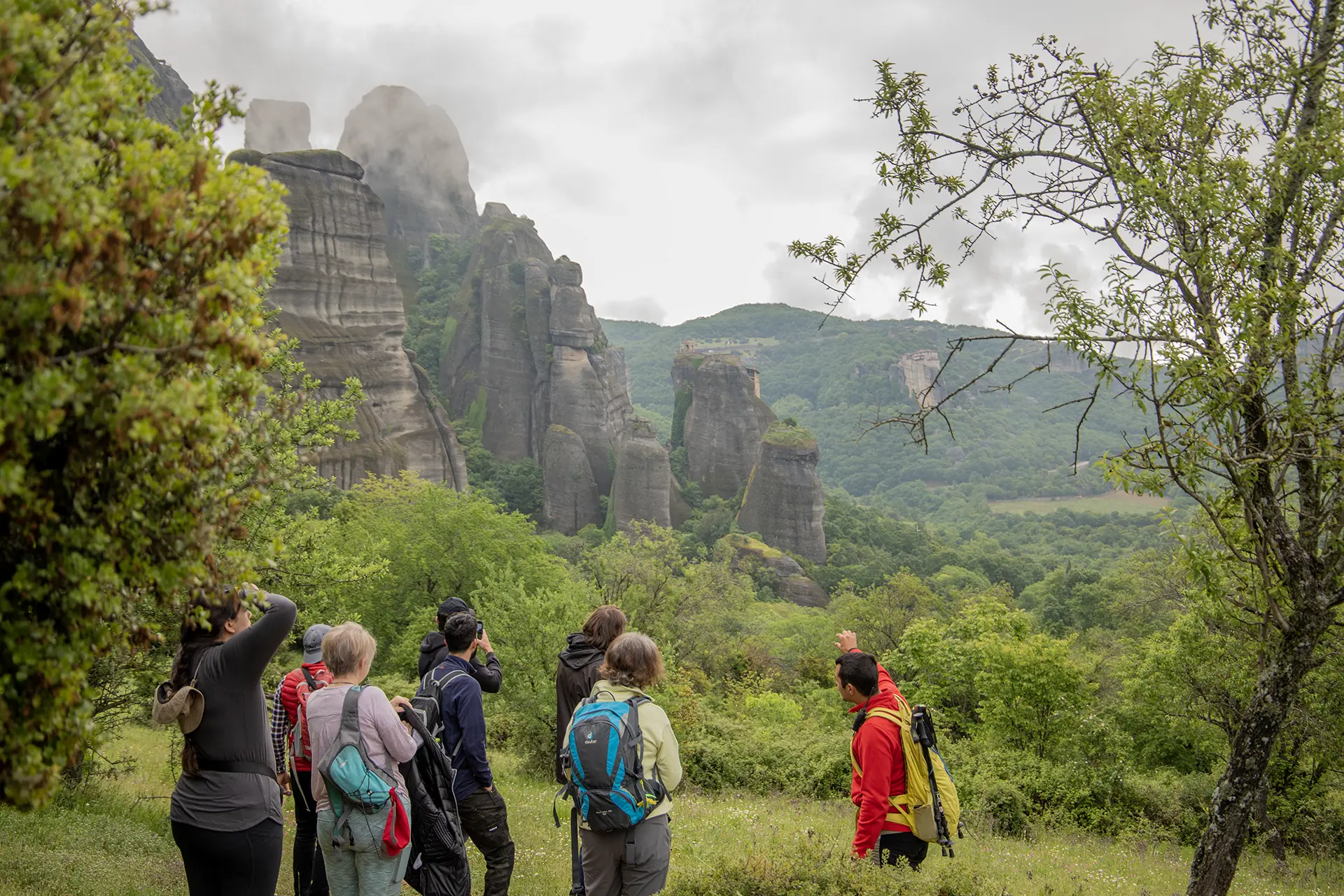 Travelers hiking on an ancient trail beneath the rocks of Meteora